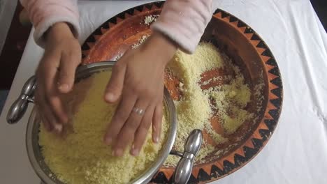 woman put the semolina of couscous in a steamer to steaming it , at home