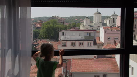 little girl looking out window at city