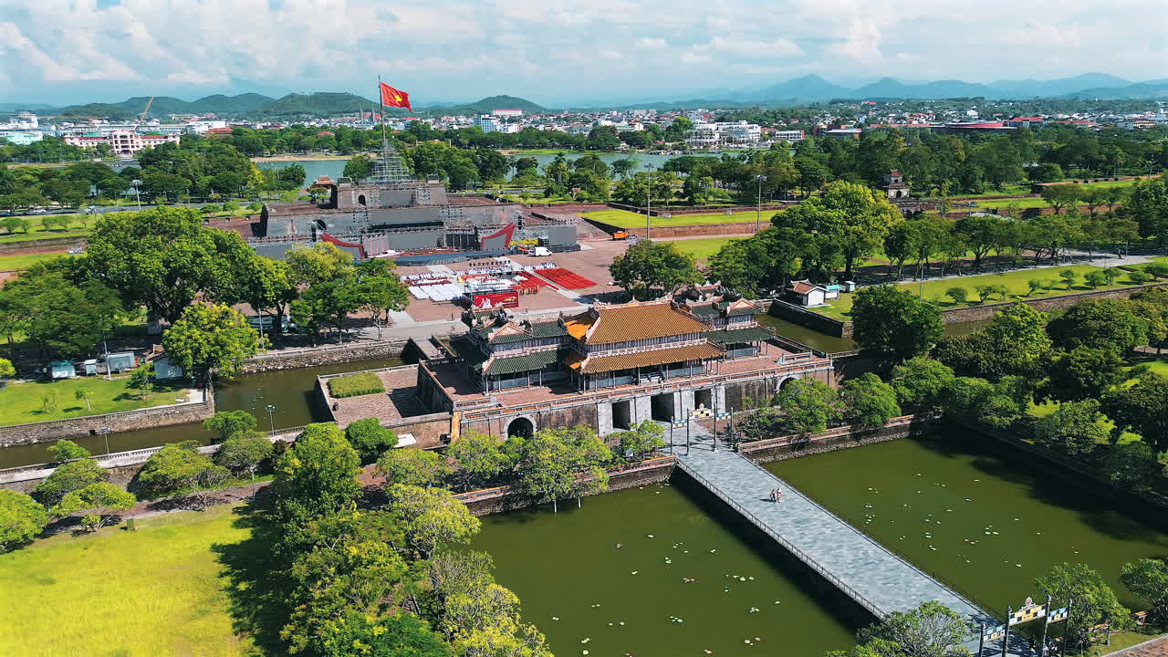 Một bức ảnh chụp từ trên cao với góc cao tuyệt đẹp ghi lại lối vào chính của Kinh thành Huế, nổi bật với Ngọ Môn, Kỳ Đài đồ sộ với lá cờ Việt Nam và hào nước bao quanh,