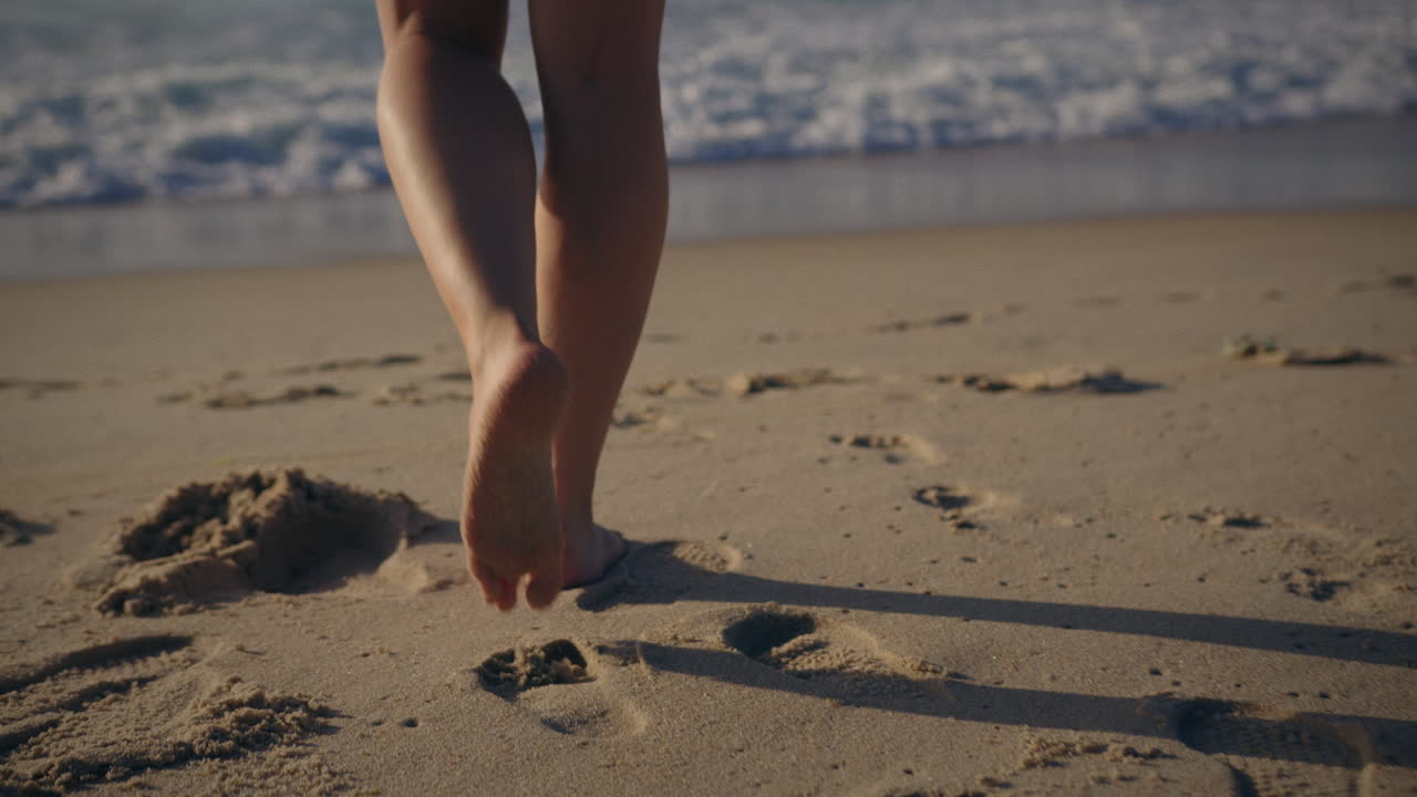 카메라 방향으로 들어오는 파도와 함께 바다를 향해 걸어가는 소녀