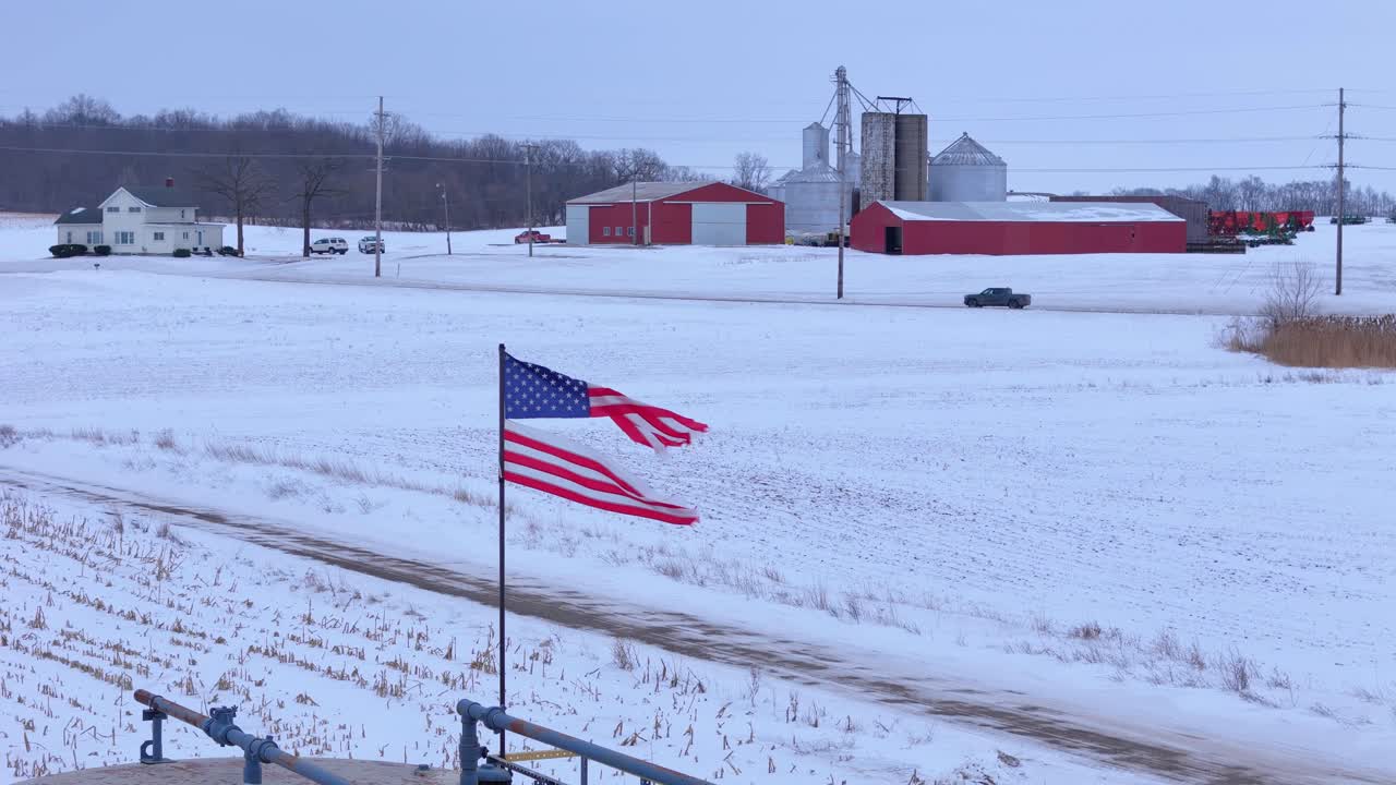 Torn American flag flying over frozen field, symbolizing decay in Saline, Michigan, USA