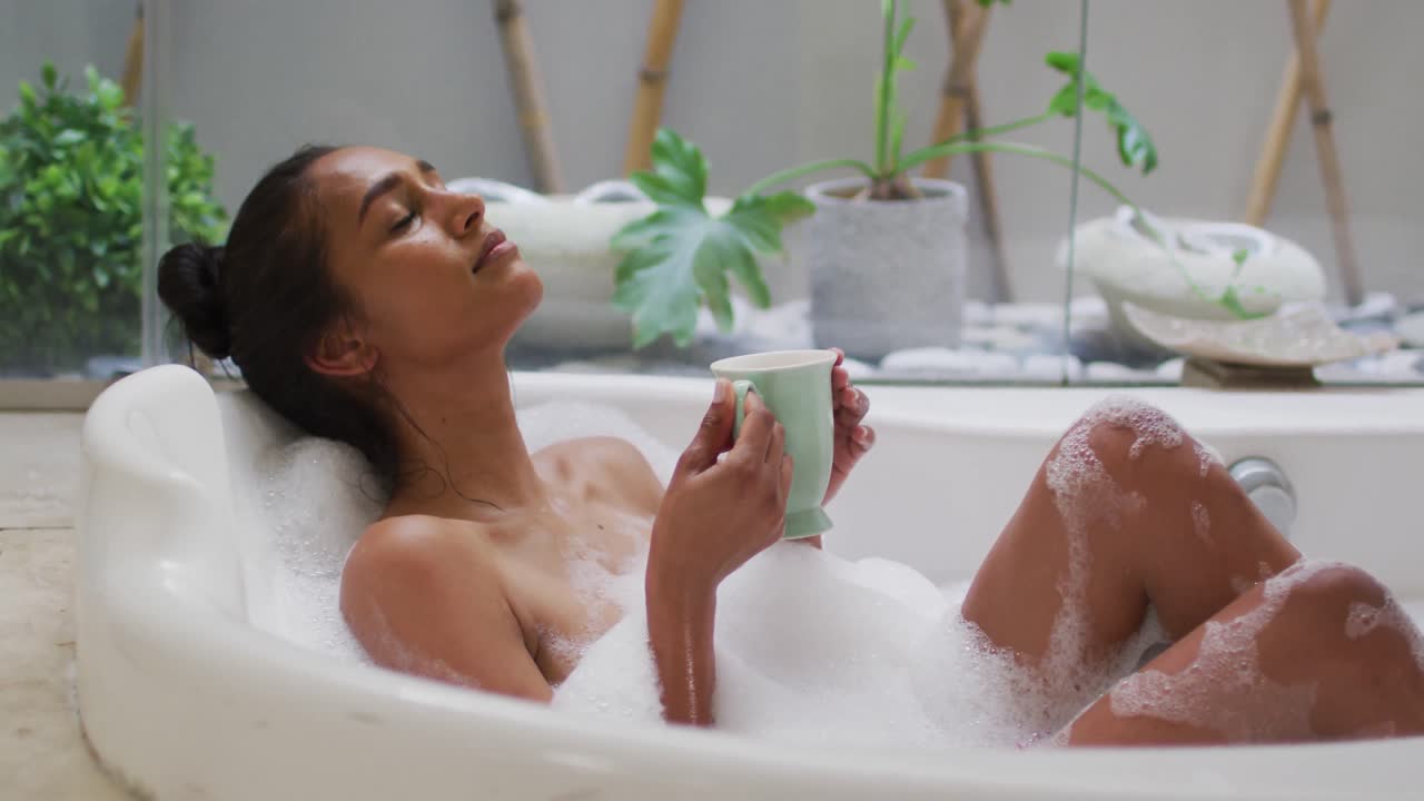 집에서 목욕탕에 누워 있는 혼성 인종 여성