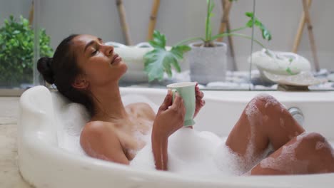 mixed race woman lying in a bathtub at home