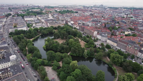 aerial view of ørstedsparken in central copenhagen, surrounded by buildings, showcasing lush green trees and lakes