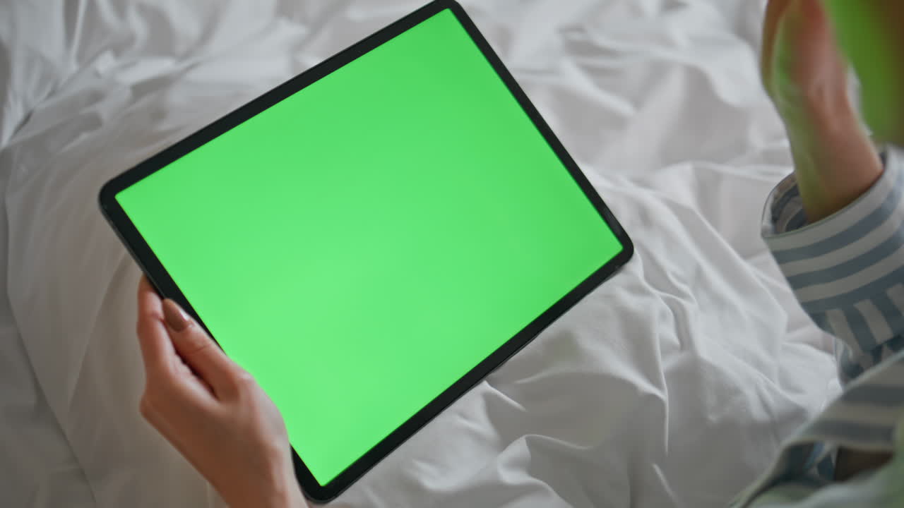 Online student looking greenscreen tablet lying comfortable white bed closeup