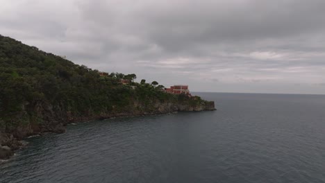 Coastal-hotel-mezzatorre-on-island-Ischia-in-Italy,-aerial-forward,-cloudy-day