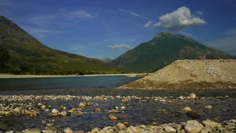 river landscape with clean water streaming on pebbles and mountains background, vjosa albania