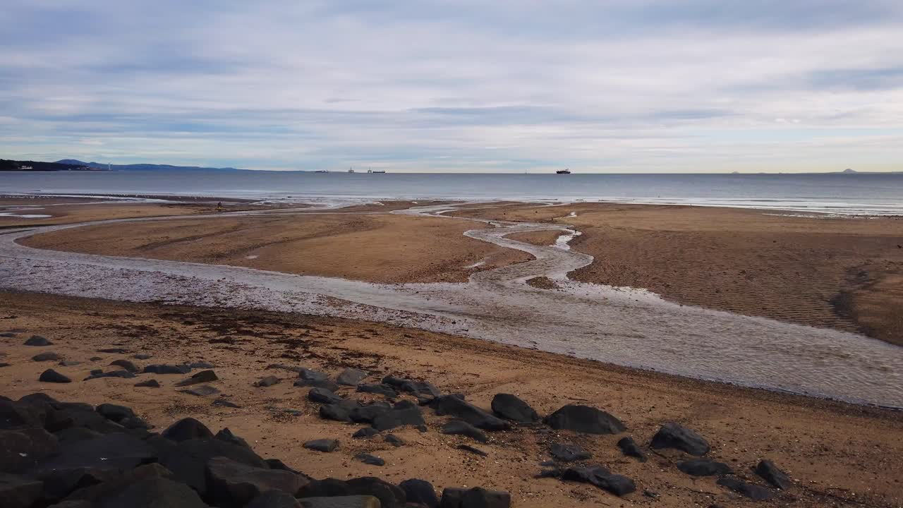 보물을 찾는 비치코머와 함께 해변을 가로질러 바다까지 지그재그 강에서 구불구불 흐르는 물