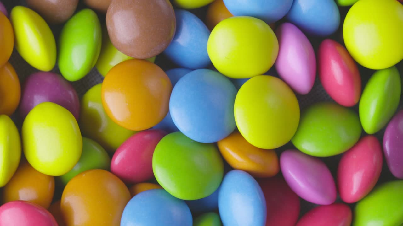 movimiento lento de primer plano de caramelos de chocolate redondos de colores, dragee. rotación y caída de caramellos de chocolate multicolores