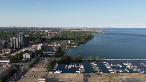 slow right to left shot of the parked boats by the water, seeing a lot of buildings of port credit, ontario, canada during the afternoon