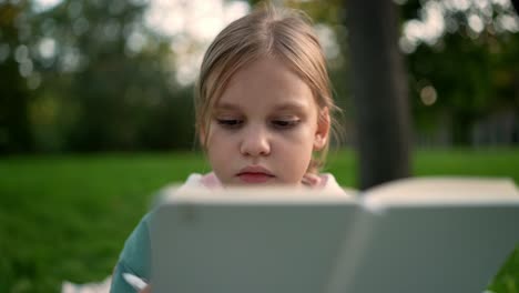 una chica leyendo en un parque.