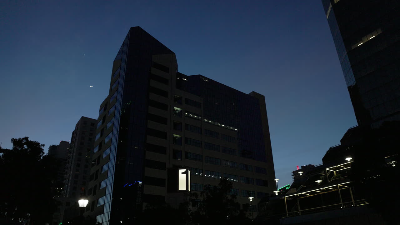 ángulo bajo de un edificio siluetado contra el cielo azul de la noche durante la hora azul con otros edificios que lo enmarcan