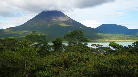 Full-shot,-above-the-trees,-scenic-view-of-Lake-Arenal-and-volcano-in-Costa-Rica,-bright-sunny-light-in-the-background