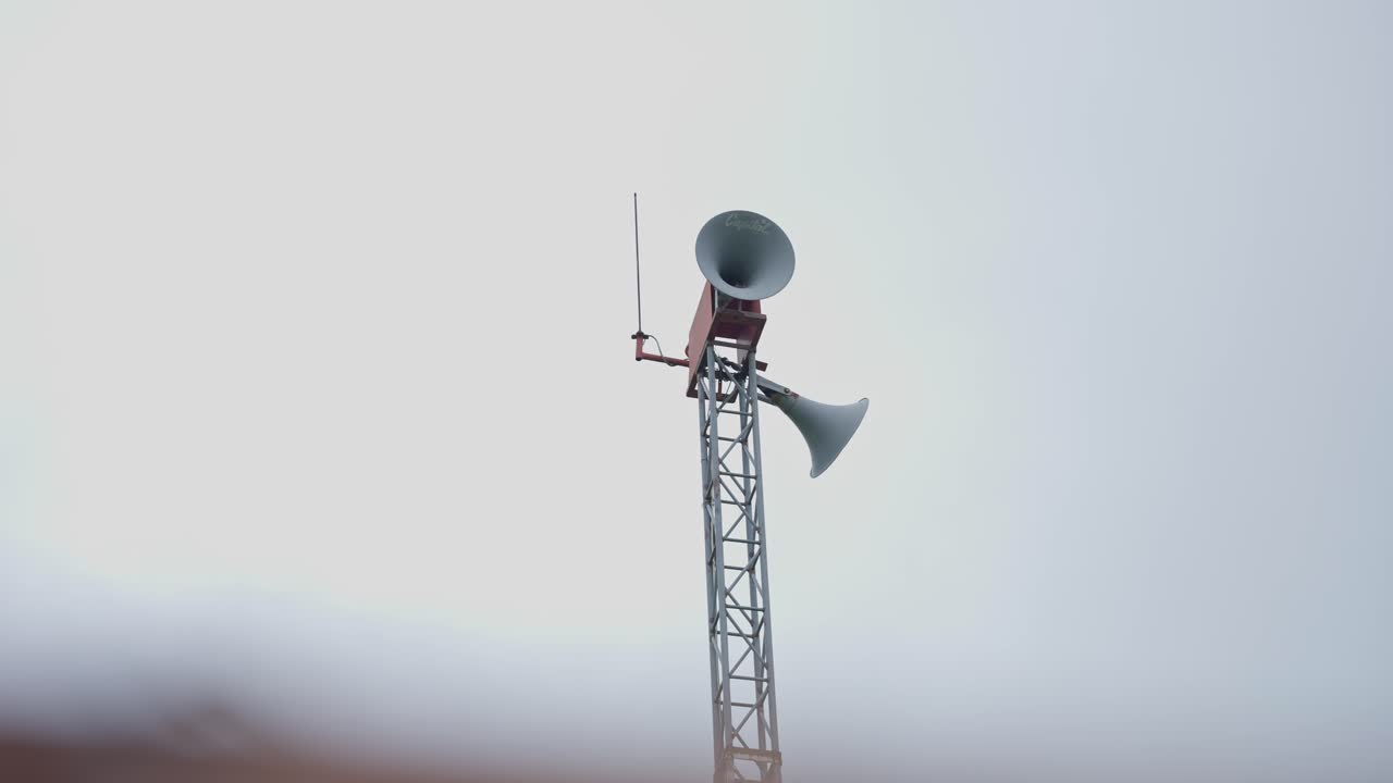 Filmato di una persona che fa un annuncio pubblico con un microfono in un contesto di villaggio. Mette in evidenza la comunicazione rurale, la messaggistica della comunità e gli eventi locali.