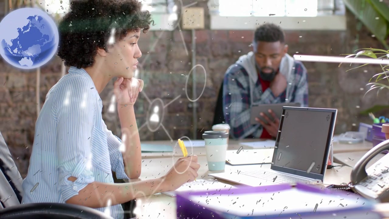 Woman writing at desk while man tapping tablet, initiating AR data cards showing business links
