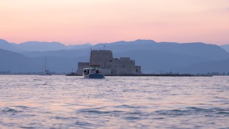 Hermosa-Puesta-De-Sol-Rosa-En-El-Paisaje-Marino-Del-Castillo-De-Bourtzi-Con-Un-Barco,-Grecia-A-Cámara-Lenta