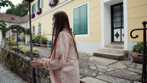 young woman using a phone in front of an old building