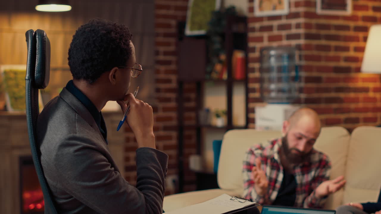 Male psychotherapist writing notes at therapy consultation