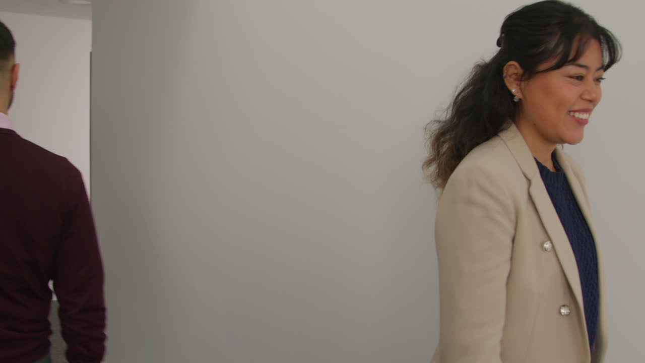 남자와 여자 교사들이 학교 건물의 복도를 함께 걸어가면서 지나간다.