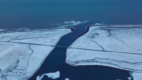 Aerial-panoramic-view-over-the-shoreline-of-diamond-beach,-covered-in-snow,-at-dusk