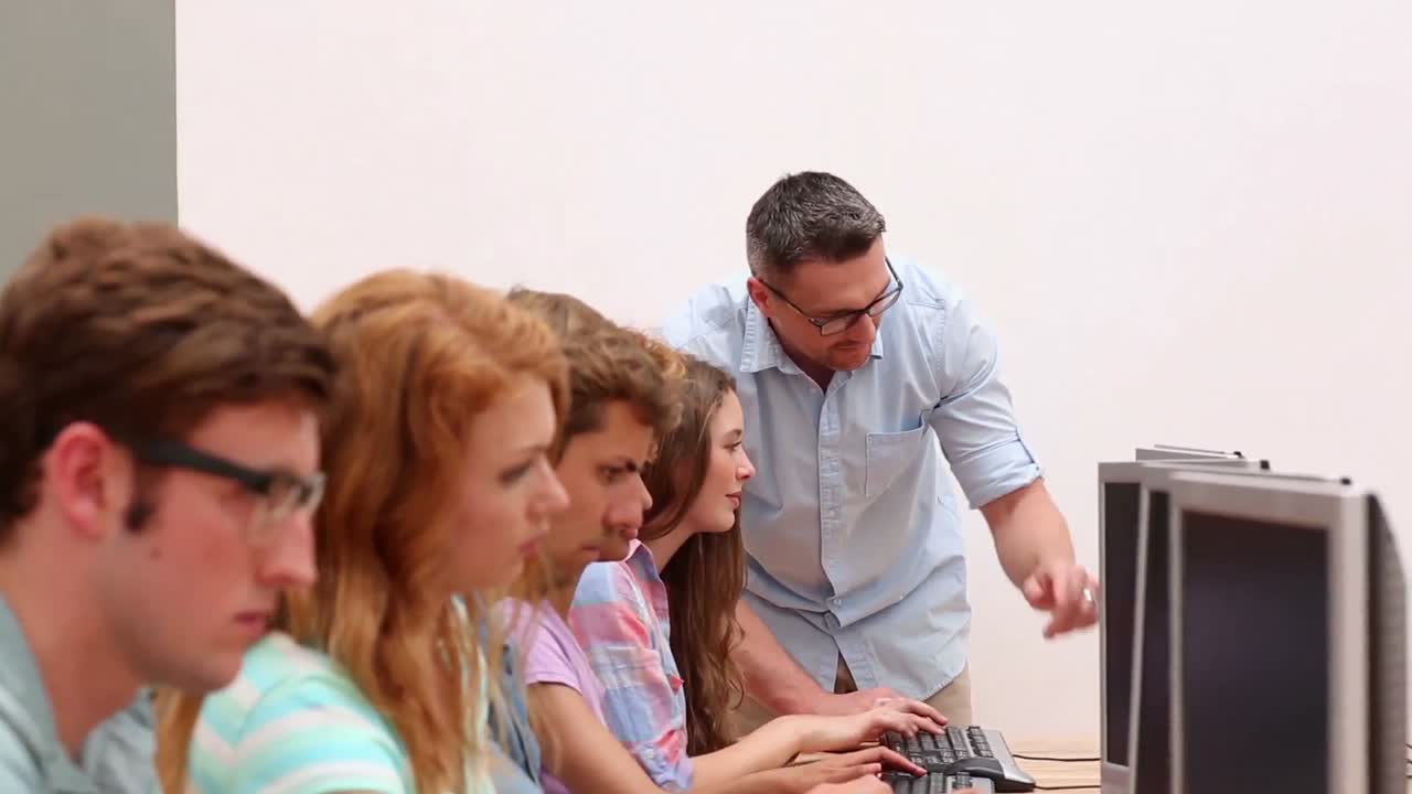 estudiantes trabajando en la sala de computadoras con el profesor