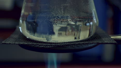 close up of erlenmyer flask that is being heated by a bunsen burner condensation on top, heat waves visible in flask