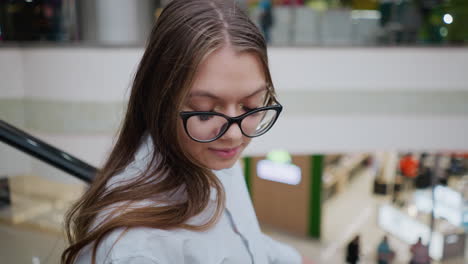 lady on escalator with glasses intently looking at something in a busy modern mall, capturing her focused expression and dynamic retail backdrop