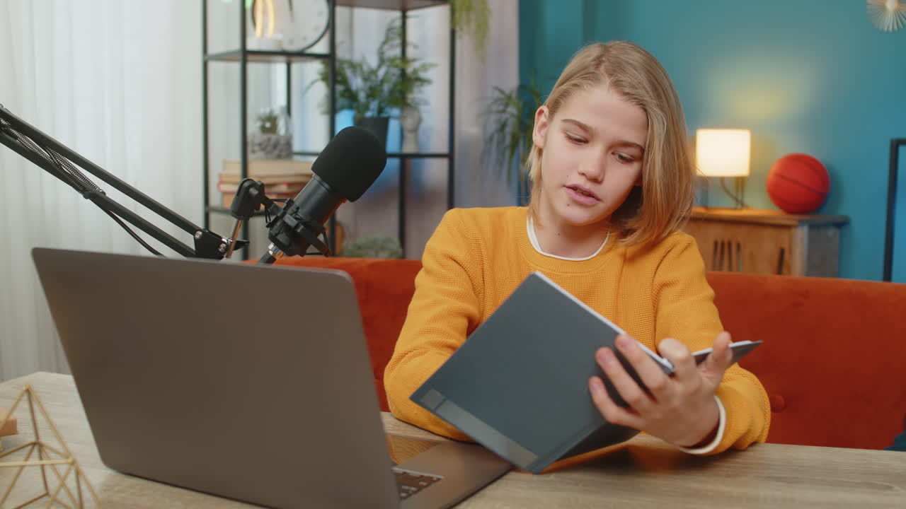 Teenager boy writing blog on laptop preparing for online stream with studio microphone at home