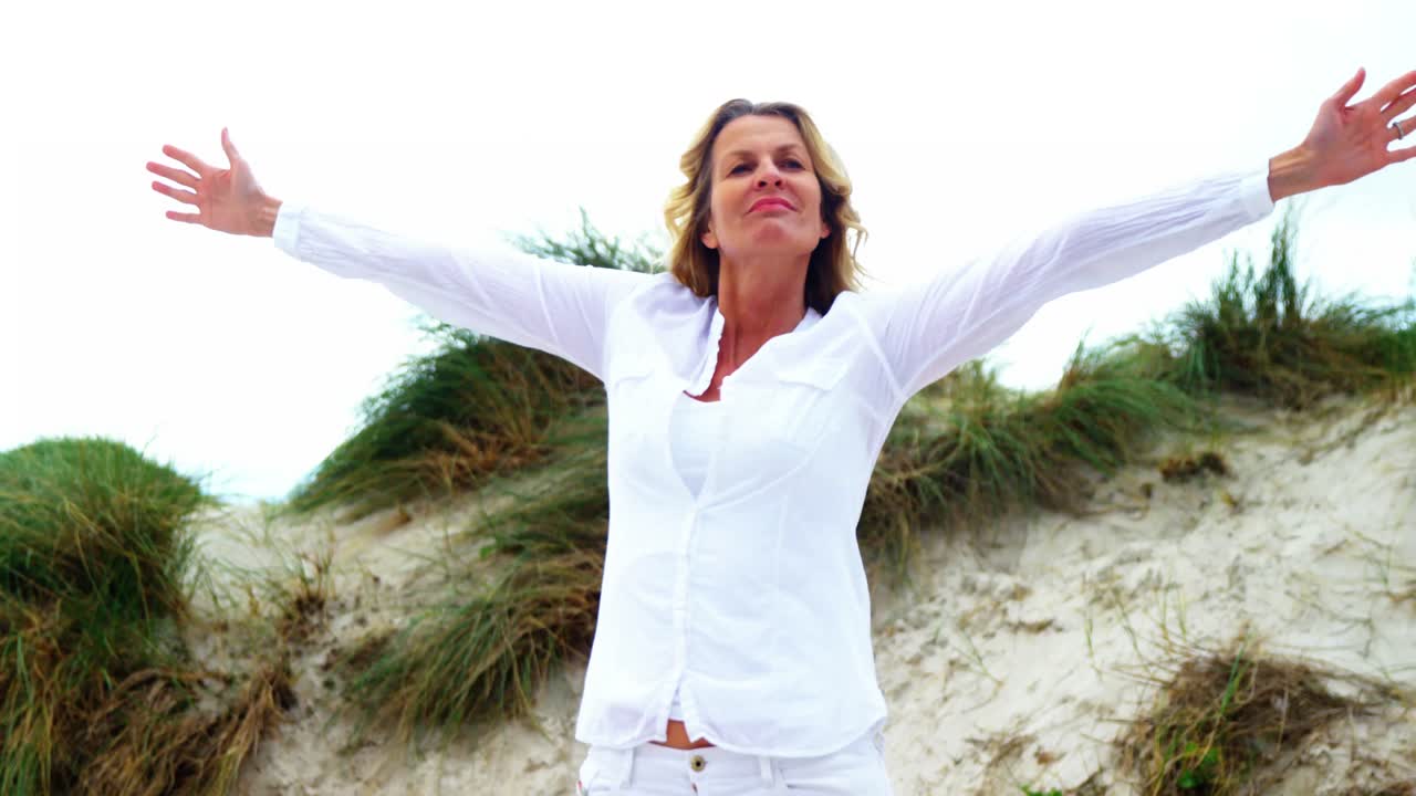 mujer madura con los brazos extendidos en la playa