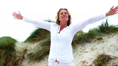 Mature-woman-with-arms-outstretched-at-beach