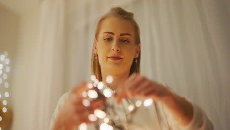 home preparations for christmas woman untangles lights and arranges decorations