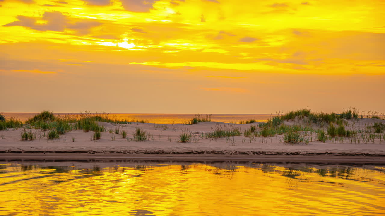물 위 에 반사 되는 황금 시간 의 빛 과 함께 모래 언덕 에 있는 풀 - 타임 스