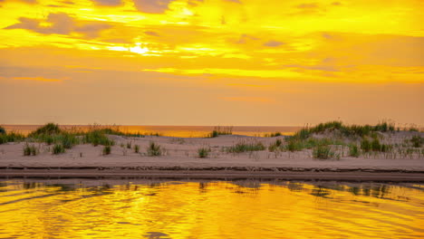 Gras-Auf-Einer-Sanddüne-Mit-Goldenem-Stundenlicht,-Das-Sich-Im-Wasser-Spiegelt---Zeitraffer