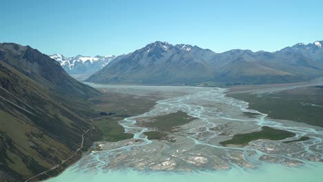 Cámara-Lenta:-Ríos-Trenzados-En-El-Hermoso-Lago-Glaciar-Azul-Pukaki,-Parque-Nacional-Aoraki-Mount-Cook,-Alpes-Del-Sur,-Nueva-Zelanda-Con-Montañas-Rocosas-Cubiertas-De-Nieve-En-El-Fondo-Del-Vuelo-Panorámico-En-Avión