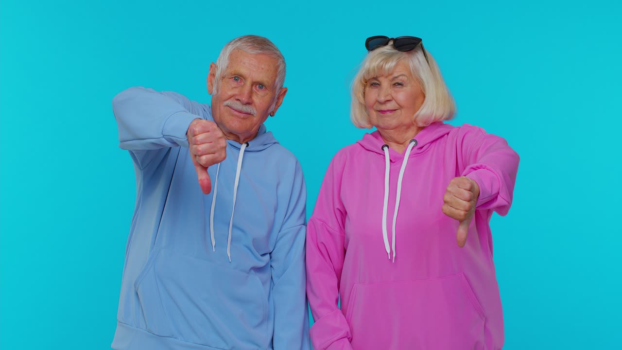 Senior grandfather grandmother showing thumbs down sign gesture, disapproval, dissatisfied, dislike
