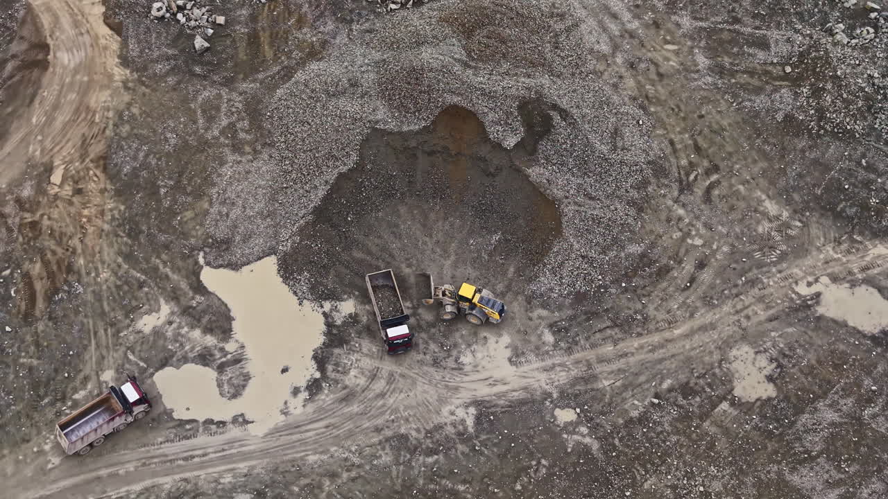 Granite quarry operation in daytime with trucks and machinery working on site for stone extraction and transportation