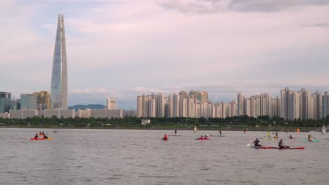 gente disfrutando del río hangang recreativo - windsurf, paddle surf y kayak con el horizonte de la ciudad de seúl en el fondo, lotter world tower