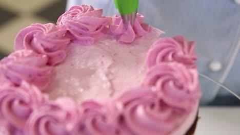 decorando un pastel rosa con rosetas de crema batida