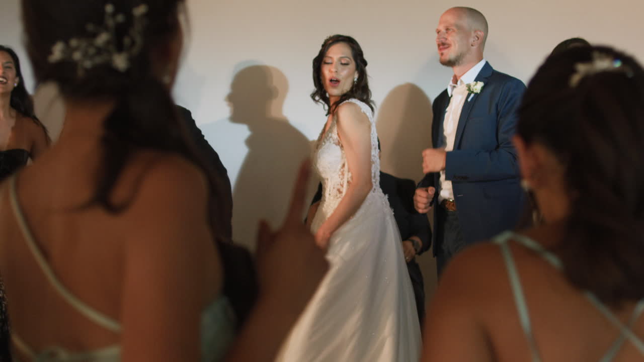 Clip of a wedding where the newlyweds dance happily with their guests and bridesmaids.