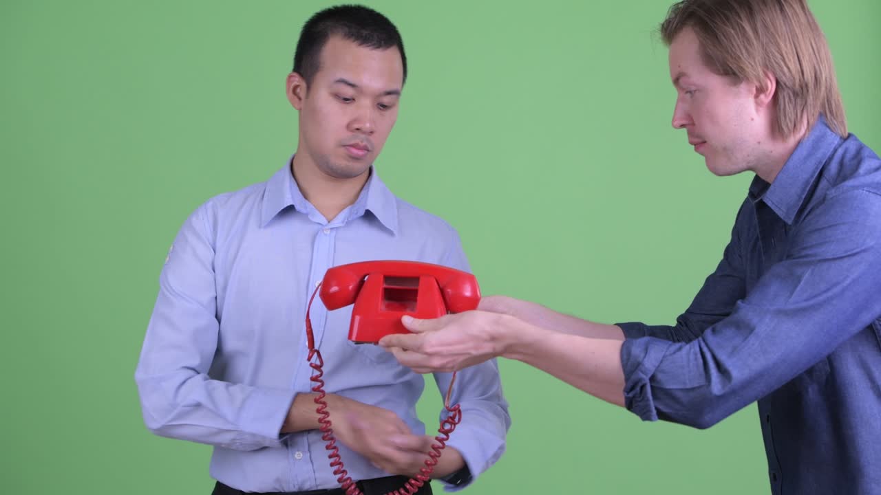 사업가 는 초록색 스튜디오 배경 에 지루 한 것 을 보면서 전화 로 이야기 하고 있다