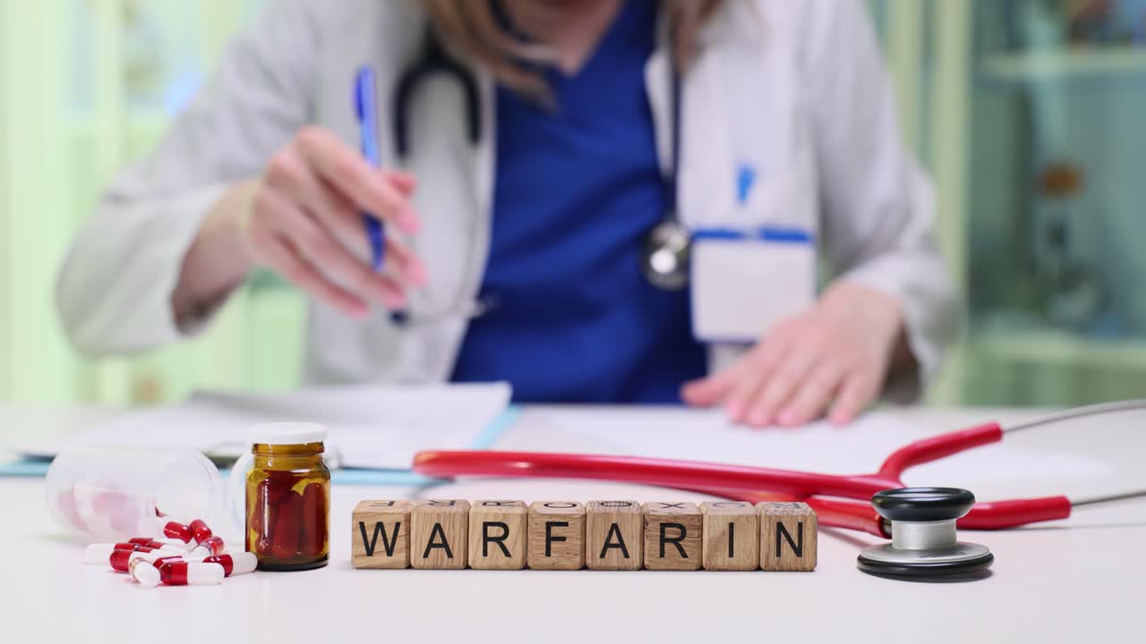 Treklosser staver ordet warfarin på et ryddig sykehusskrivebord.