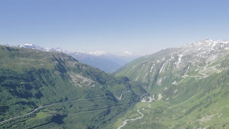 Swiss-Alps-mountain-range-valley-with-road-and-river,-Switzerland,-aerial-view