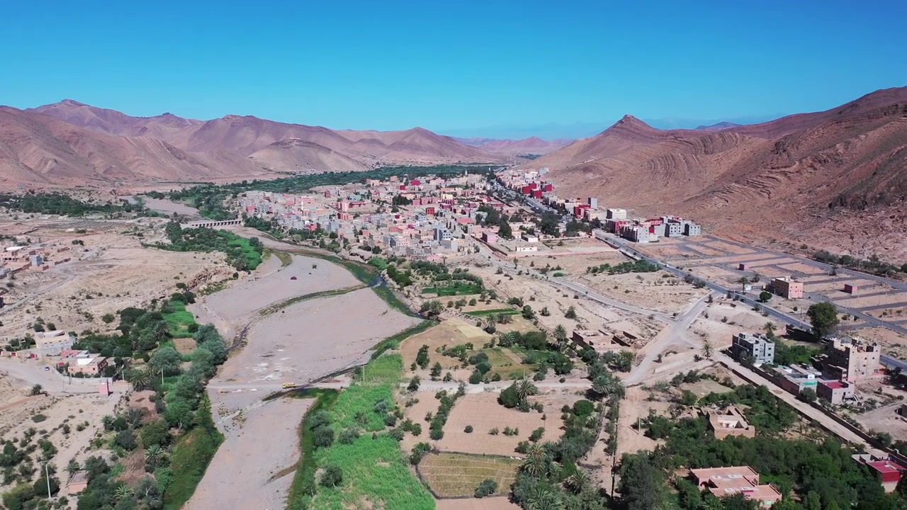 Yemyeşil vaha manzaraları, dağ vadileri ve geleneksel çöl mimarisinin Fas'ın en ikonik seyahat destinasyonlarından birini yarattığı Ouarzazate'nin drone panoramik görünümü.