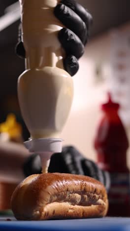 preparing a hot dog with mayo