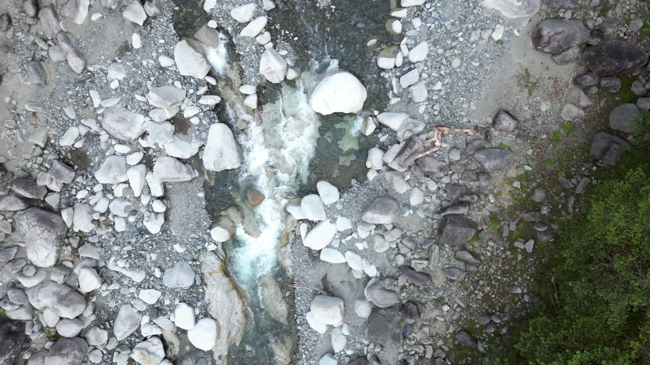 Top down rotating drone view over riverbed in lush forest