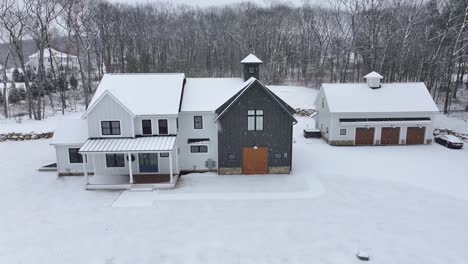 snow-covered single family house with three garage building and parking in usa. snowfall and snowflakes in american suburb. aerial orbit shot.