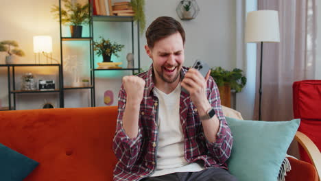 surprised excited man winner holding smartphone reading good news amazed by online bet bid game win