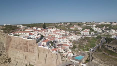 Cinematic-pedestal-dolly-in-shot-capturing-natural-swimming-pool-and-clifftop-village-in-Azenhas-do-Mar