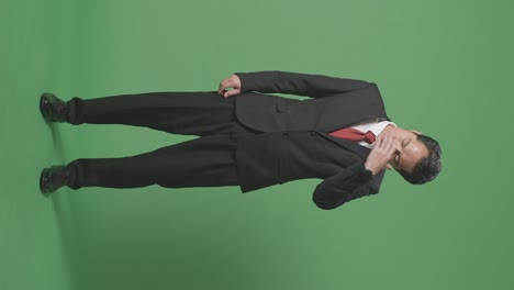 full body of asian business man having headache while standing in front of green screen