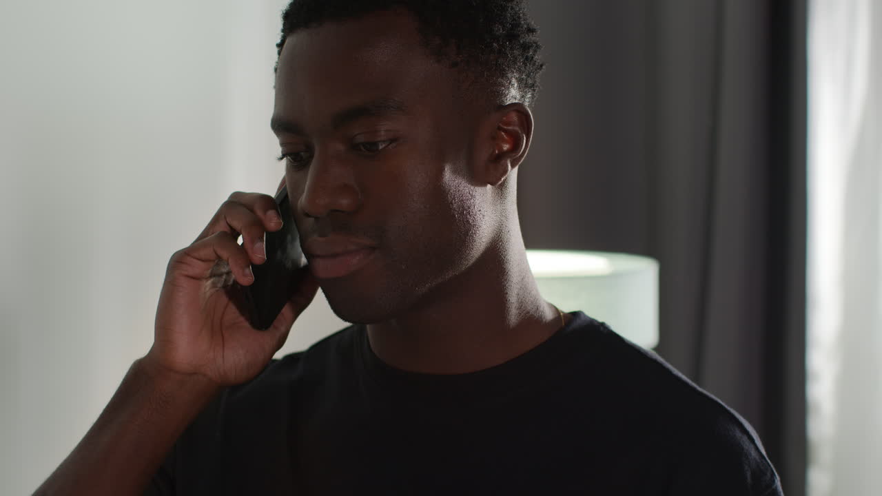 Young Man At Home Answering Call On Mobile Phone Upset After Getting Bad News